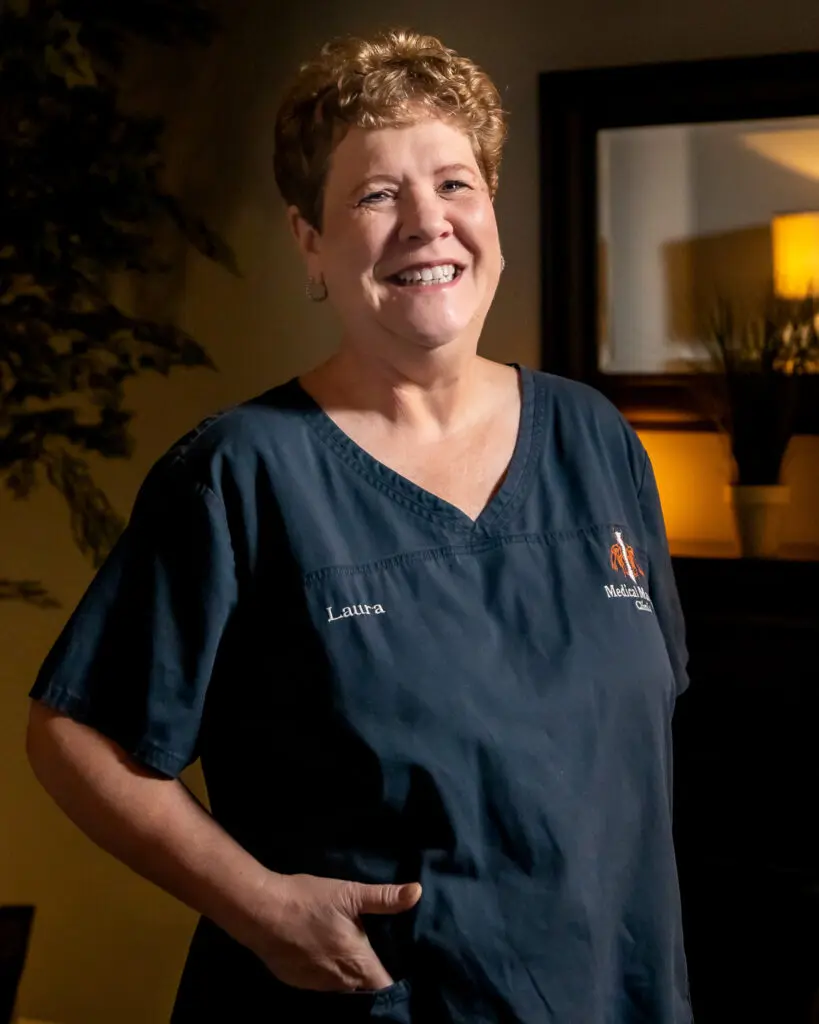 A woman in scrubs smiling for the camera.