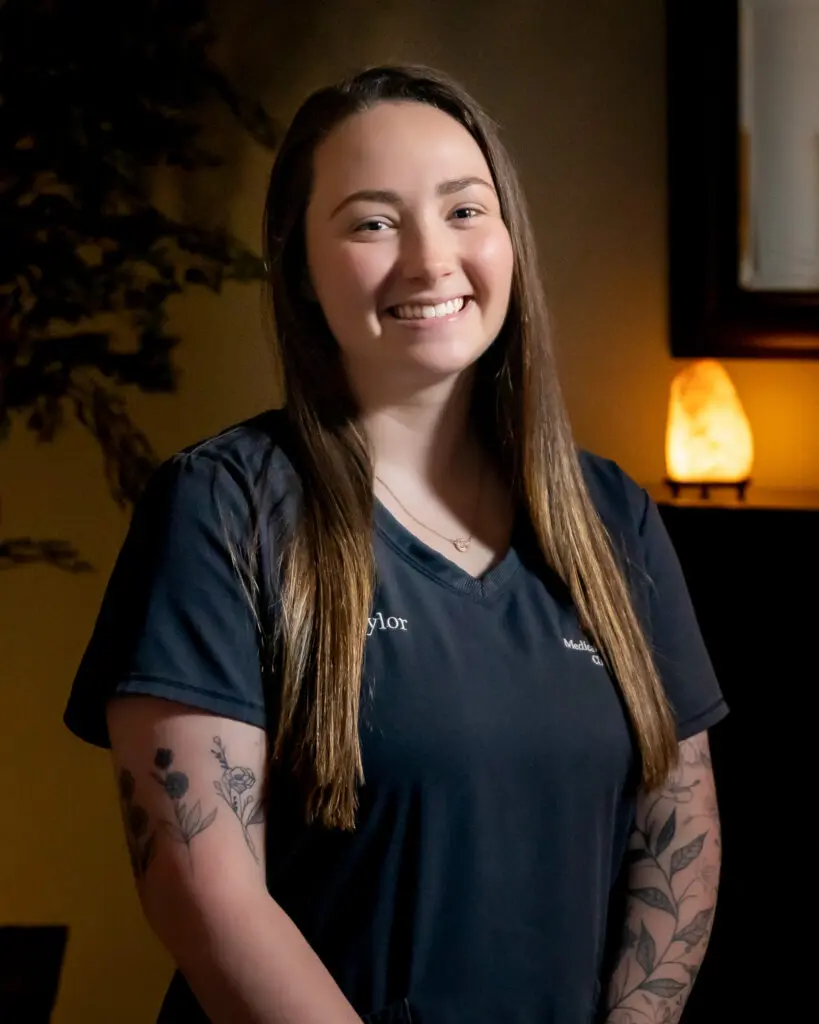 A woman with tattoos standing in front of a lamp.