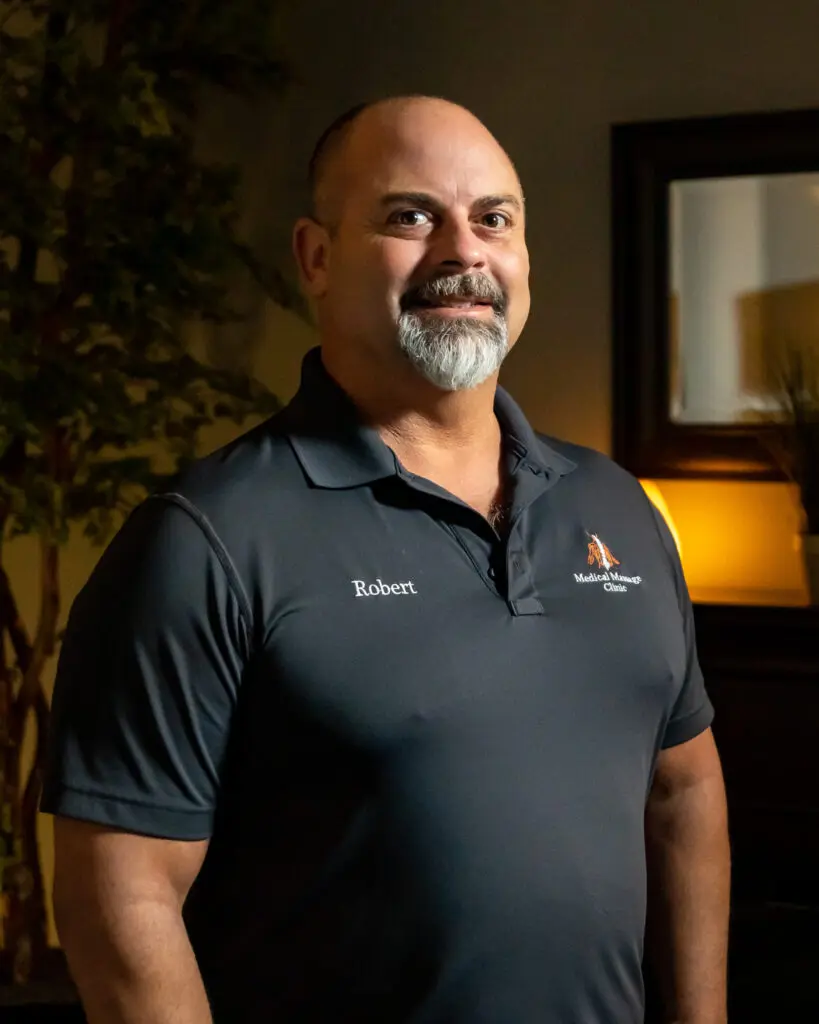 A man in black shirt standing next to tree.