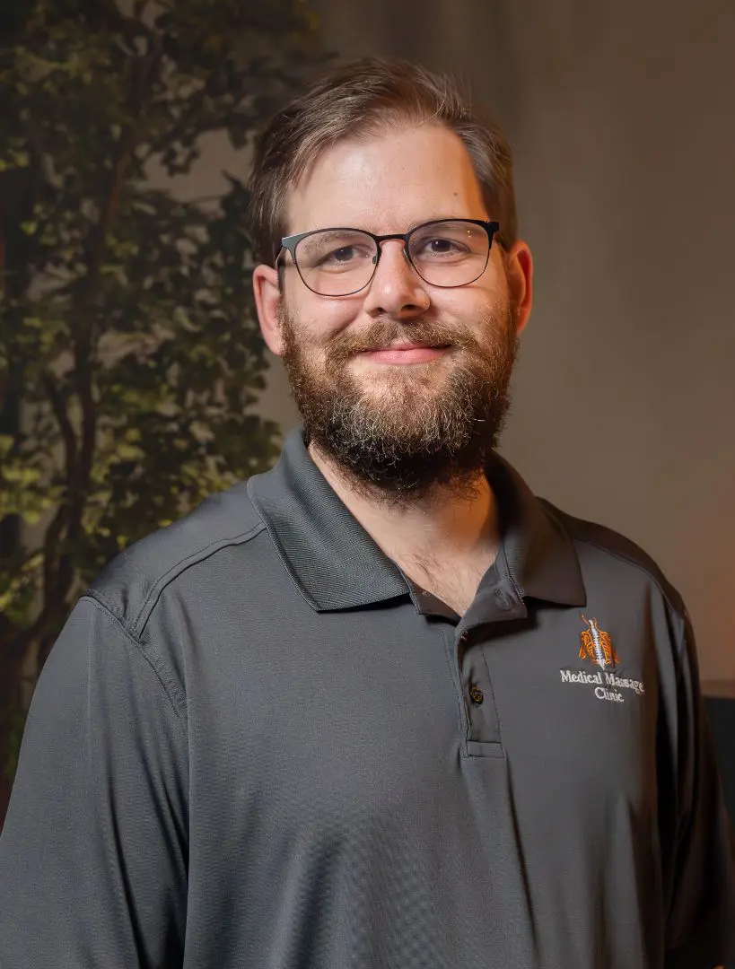 A man with glasses and beard wearing a gray shirt.