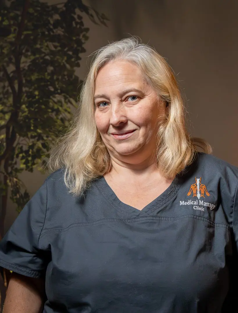 A woman in scrubs standing next to a tree.