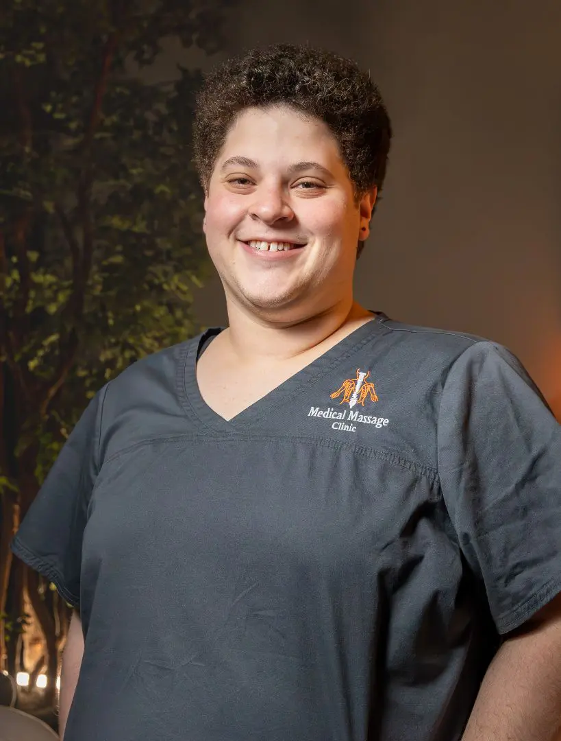 A woman in grey scrubs smiling for the camera.