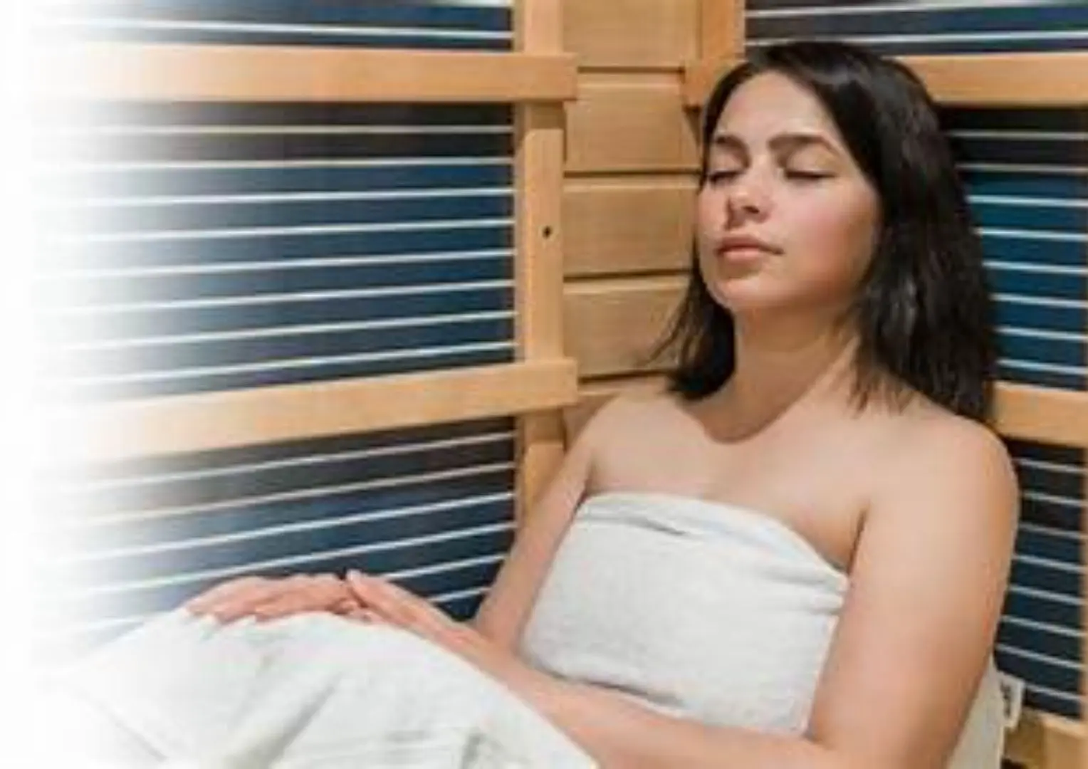 A woman sitting in the sauna with her eyes closed.